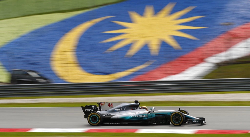 Mercedes Formula One car driving past Malaysian flag