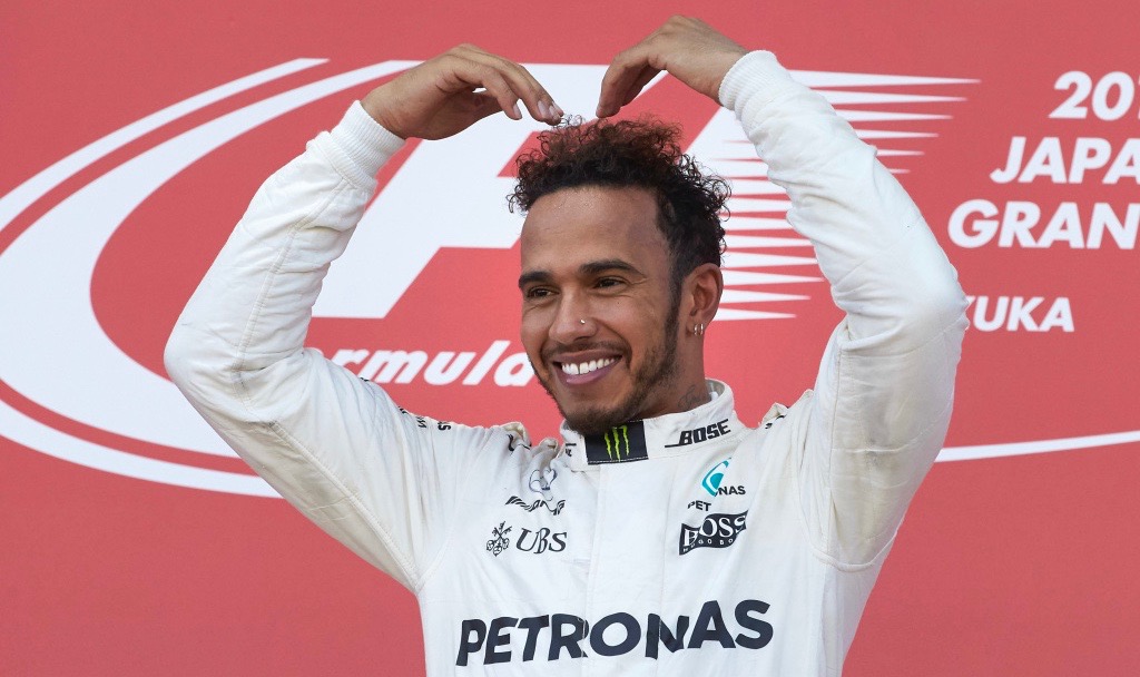 Lewis Hamilton puts hands together in heart shaped position above head.