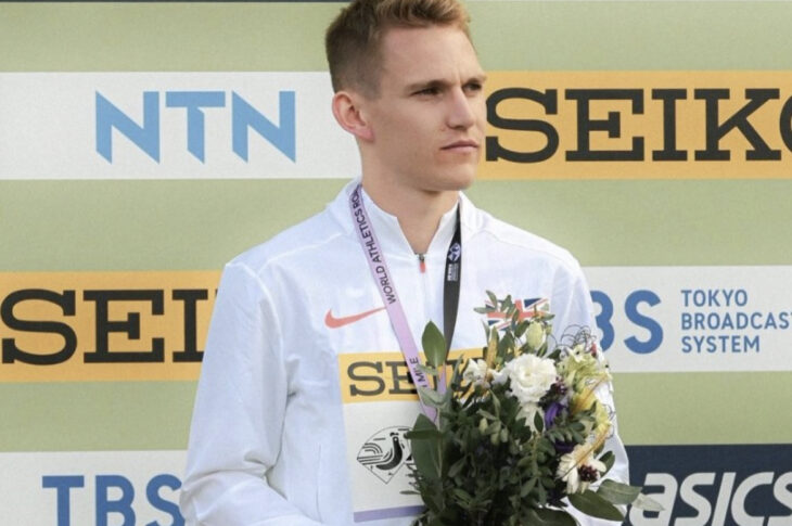 Callum Elson standing on the podium with a silver medal around his neck and flowers in his hands