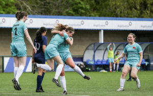 Cambridge players leap up in celebration. Hastie, the goalscorer, is embraced by teammate Neve Mayes