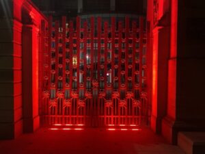 The Rose and Poppy Gates illuminated red at night