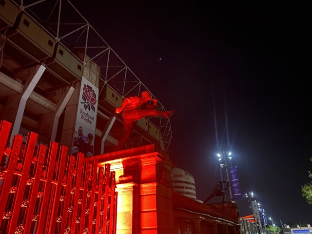The Spirit of Rugby sculptures above the Rose and Poppy Gates lit up red outside Twickenham Stadium at night
