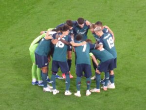 Arsenal gather in a team huddle ahead of UCL clash against RC Lens. They don their green third strip.