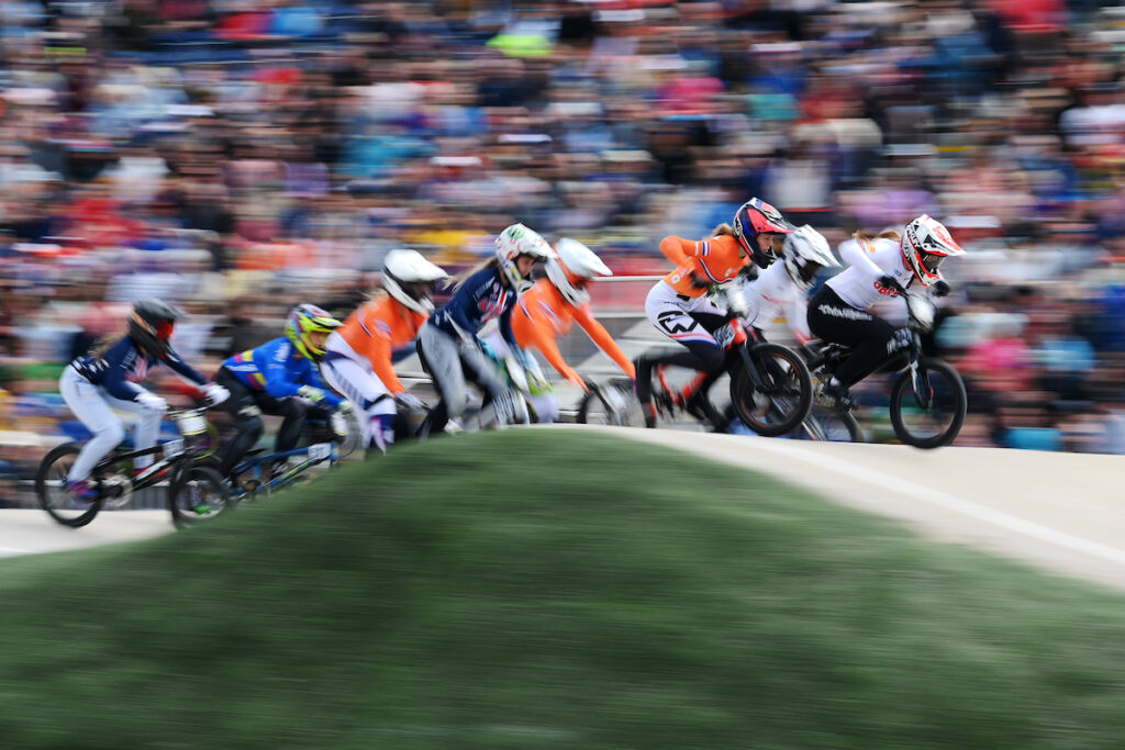 BMX racers racing over a hill on the track