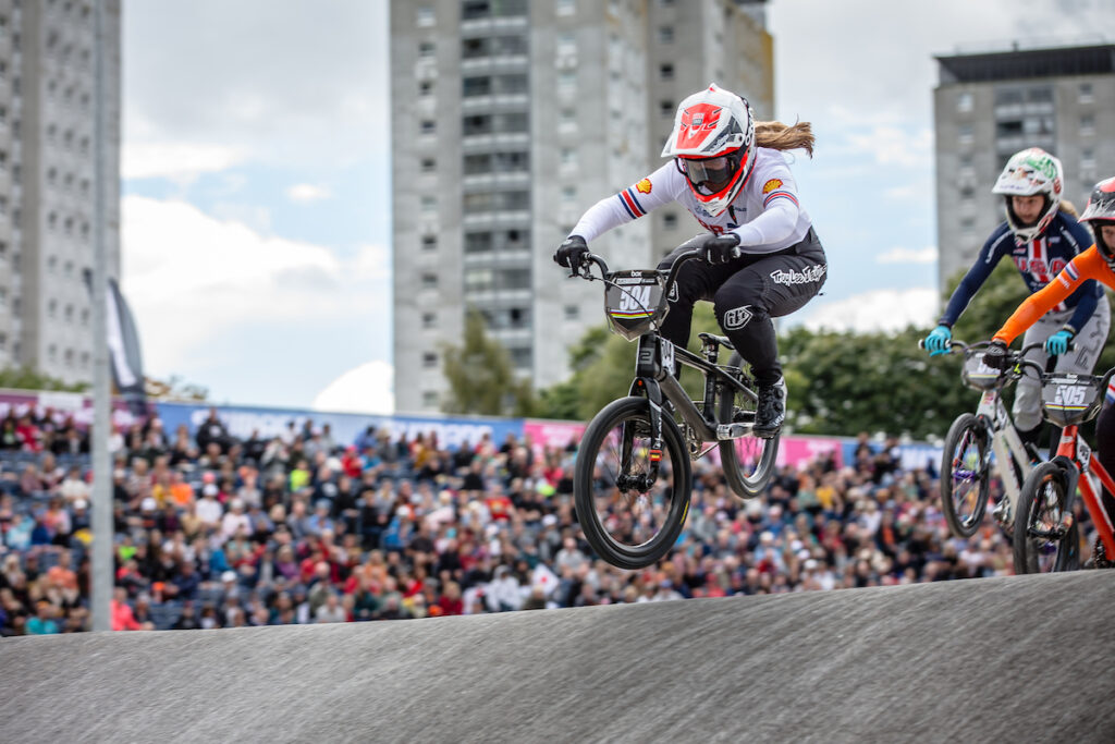 Emily Hutt racing over a hill on the Glasgow BMX track