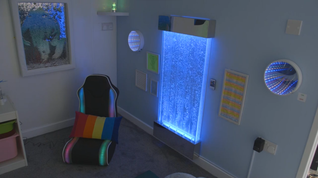 Sensory room with black chair and rainbow cushion, and different sensory textures on the wall