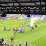 Crystal Palace life the trophy as Women's Championship champions at Selhurst Park with fire shoots behind them and golden ticker tape falling.