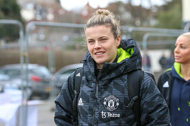 Hayley Ladd smiles in grey Manchester United coat. She will compete in the FA Cup Final on the 12th May 2024.
